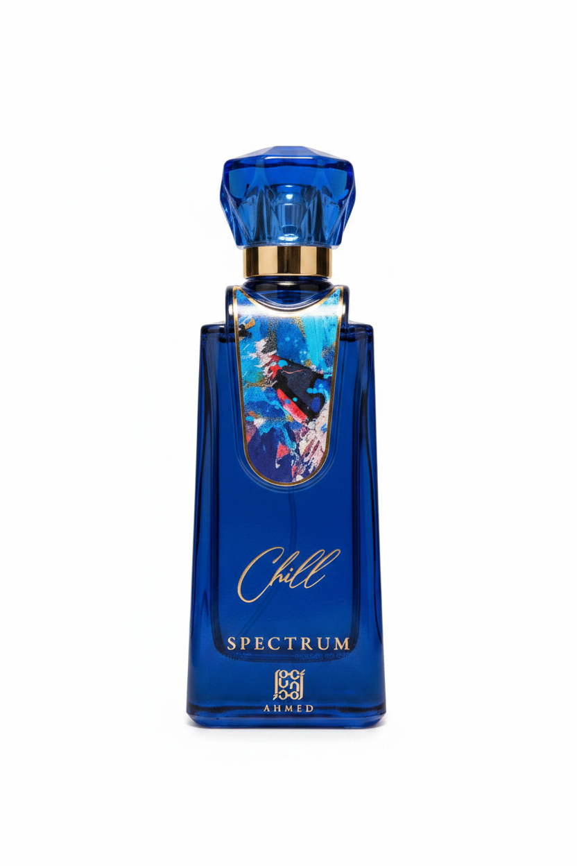 A blue glass perfume bottle with a faceted blue cap and a gold collar, featuring an artistic label of a surfer in the ocean and the text 'Chill SPECTRUM' and 'AHMED'.
